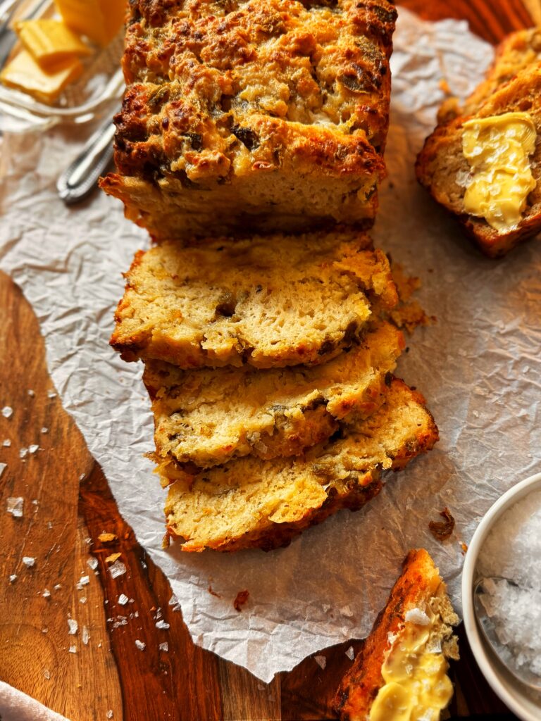 loaf of sliced cheesy green chile beer bread, butter, and flaked sea salt