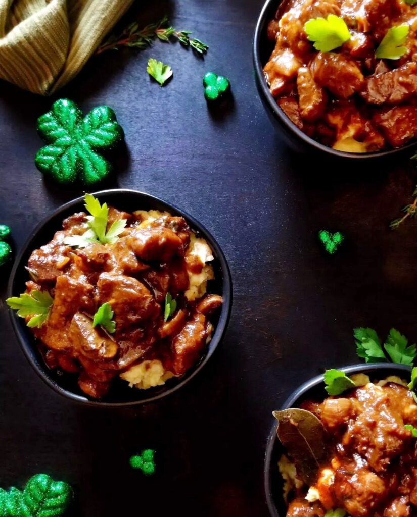 photo of bowls of beef Guinness stew on top of mashed potatoes with glittery shamrocks scattered throughout