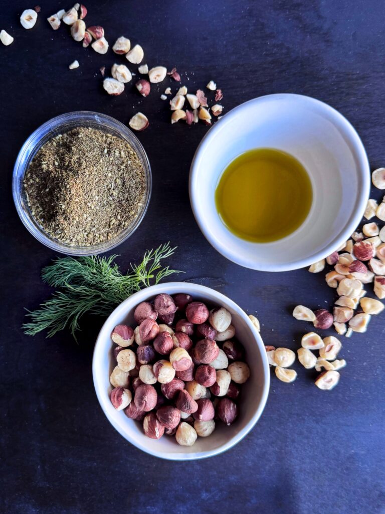 photo of small bowls filled with olive oil, chopped hazelnuts, za'atar seasoning, and fresh dill