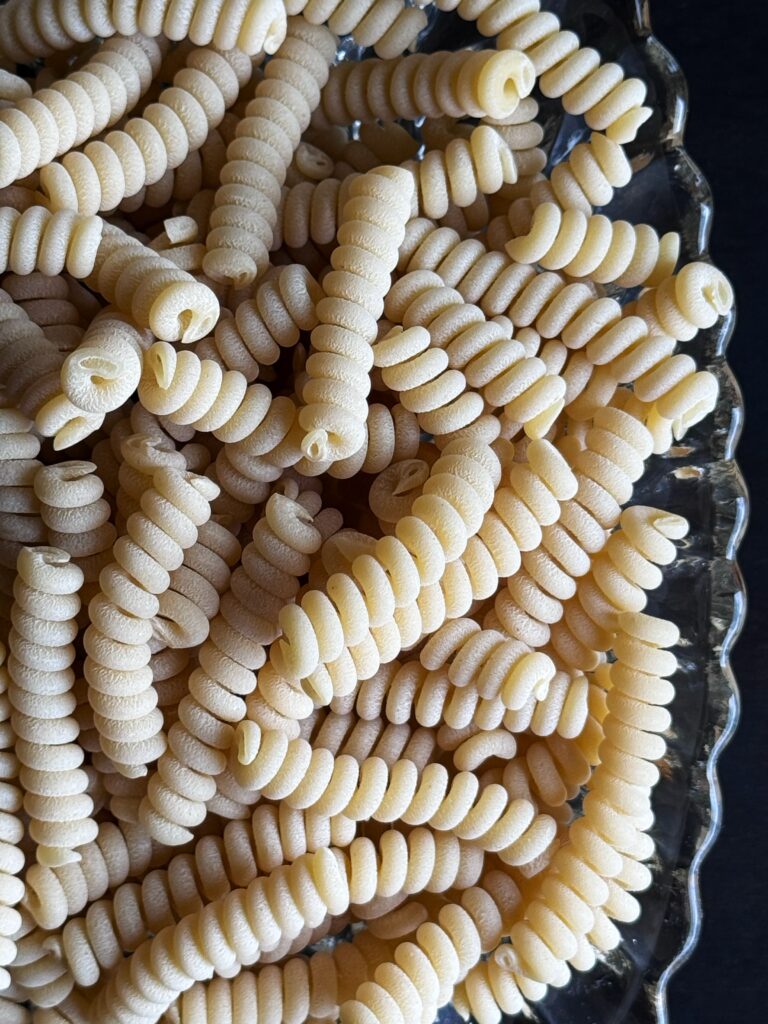 a close up photo of dried fusilli pasta in a clear crystal bowl