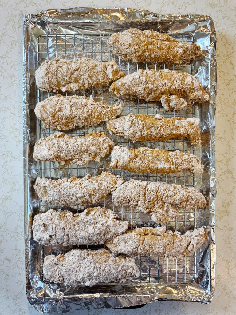 photo of breaded raw chicken tenders sitting on a wire rack