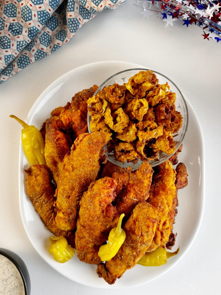 photo of a platter of fried chicken sitting on a white table top. There is also a red, white, and blue cloth and star confetti on the table